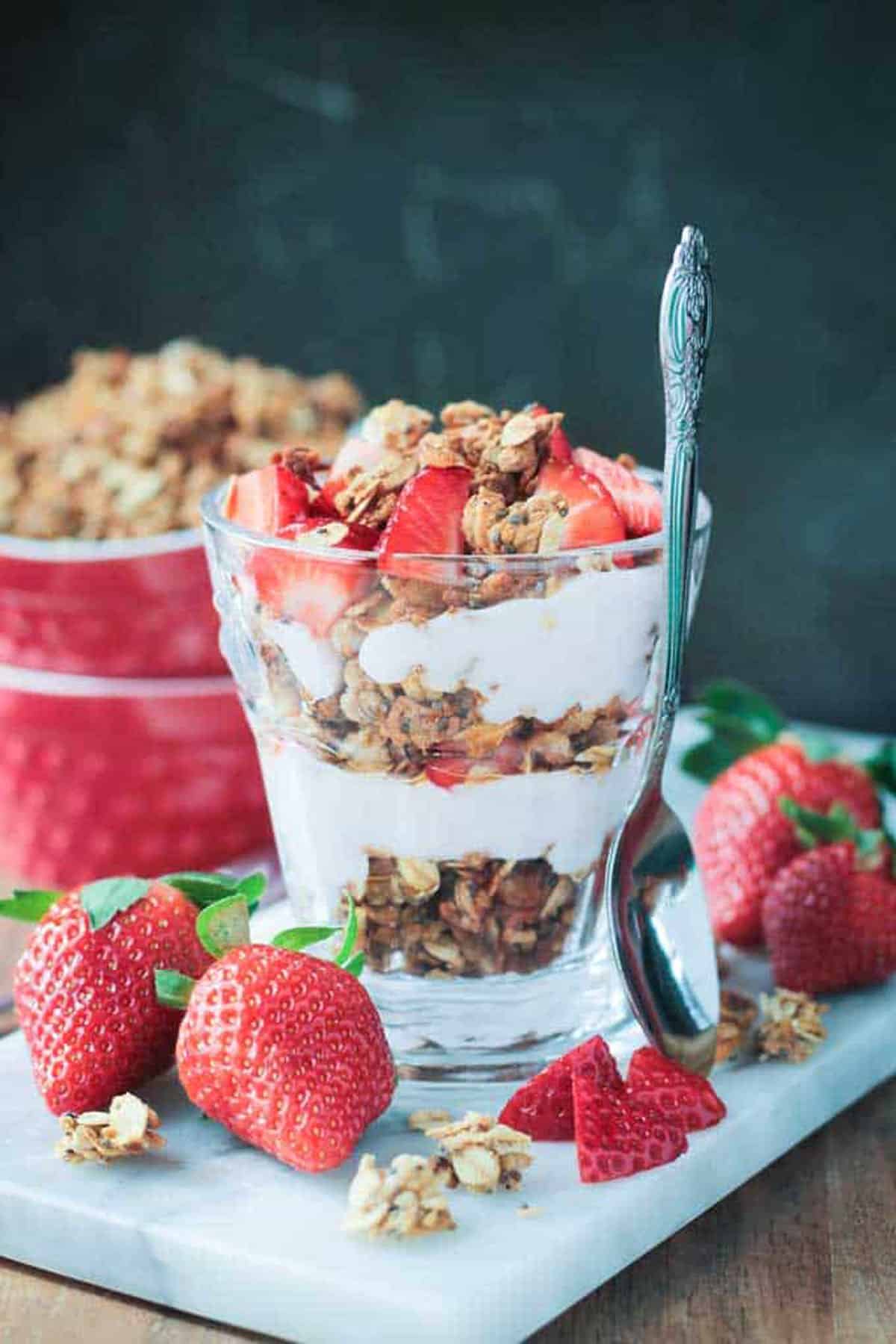 Granola and yogurt layered like a parfait in a glass and topped with fresh strawberries.