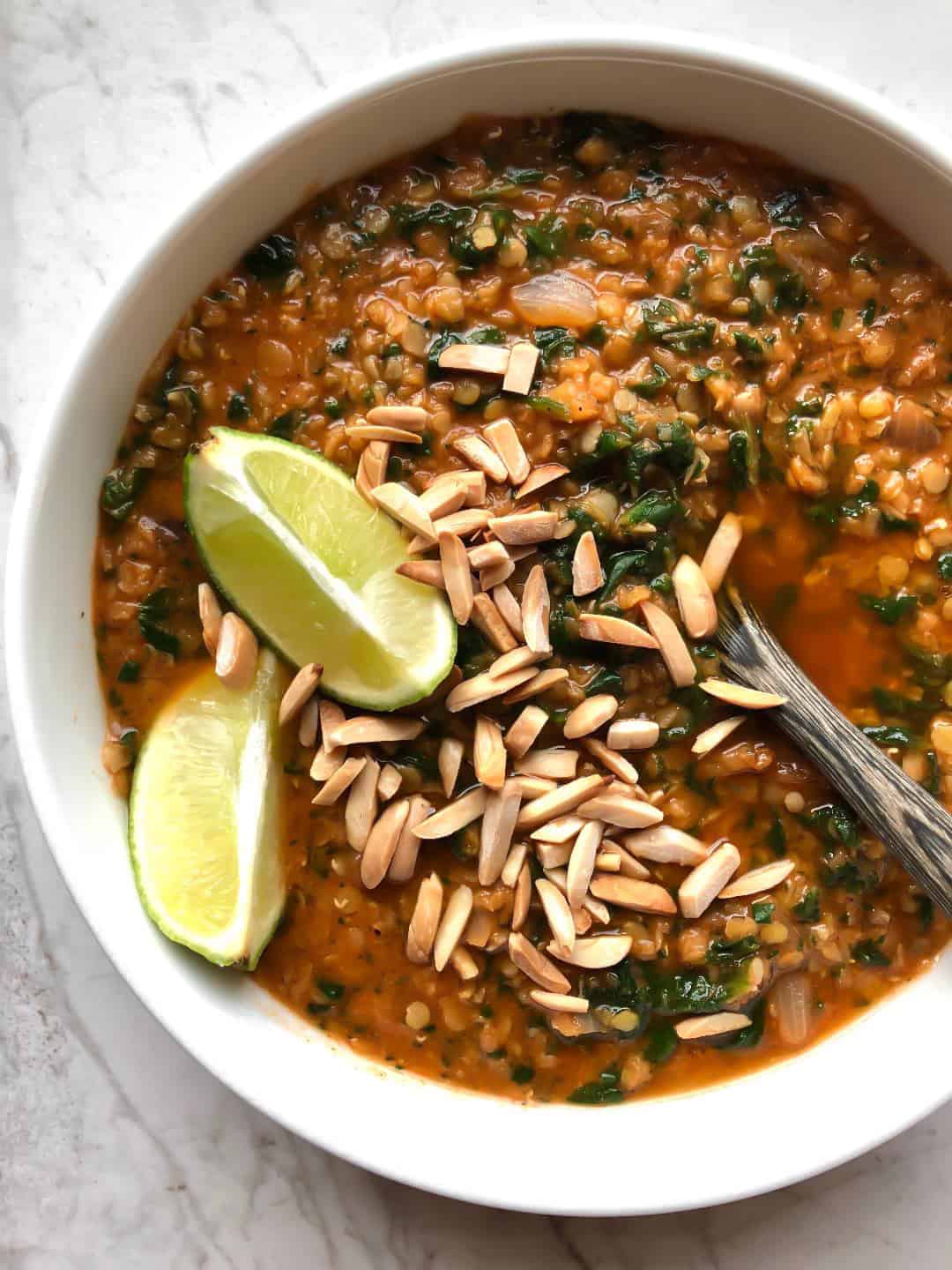 two lime wedges and slivered almonds on top of lentil soup