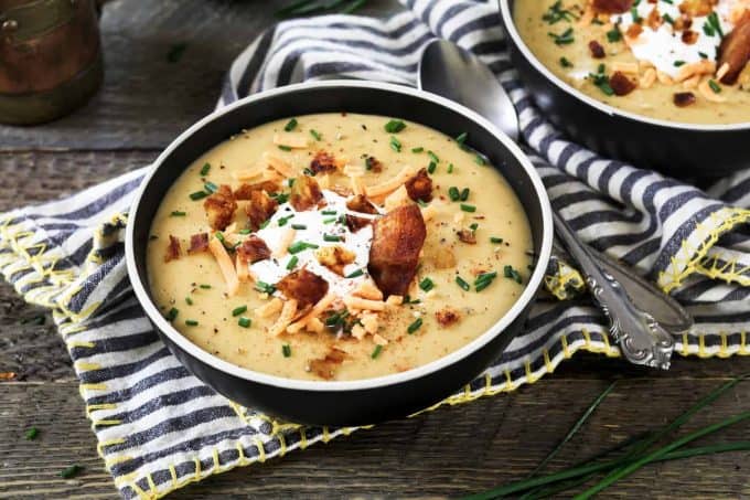 loaded baked potato soup in a dark colored bowl