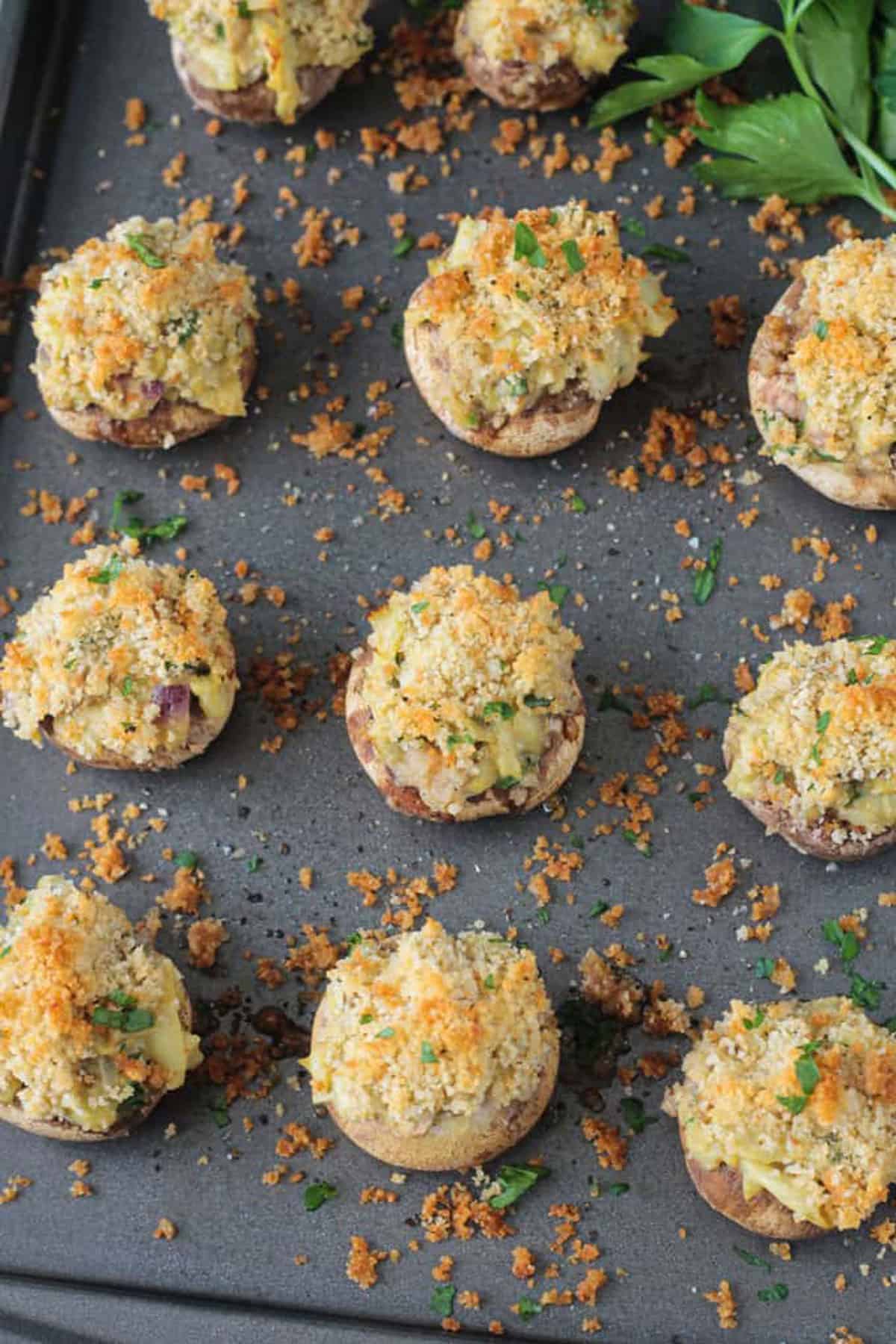 Close up of scattered breadcrumbs on a baking sheet of stuffed mushrooms.