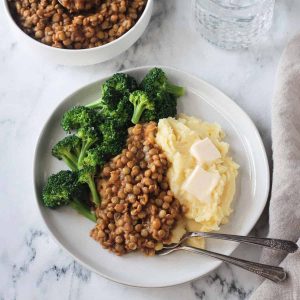 BBQ lentils with mashed potatoes and steamed broccoli on a white plate
