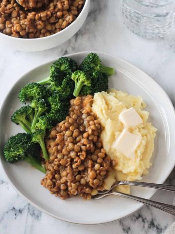 BBQ lentils with mashed potatoes and steamed broccoli on a white plate.