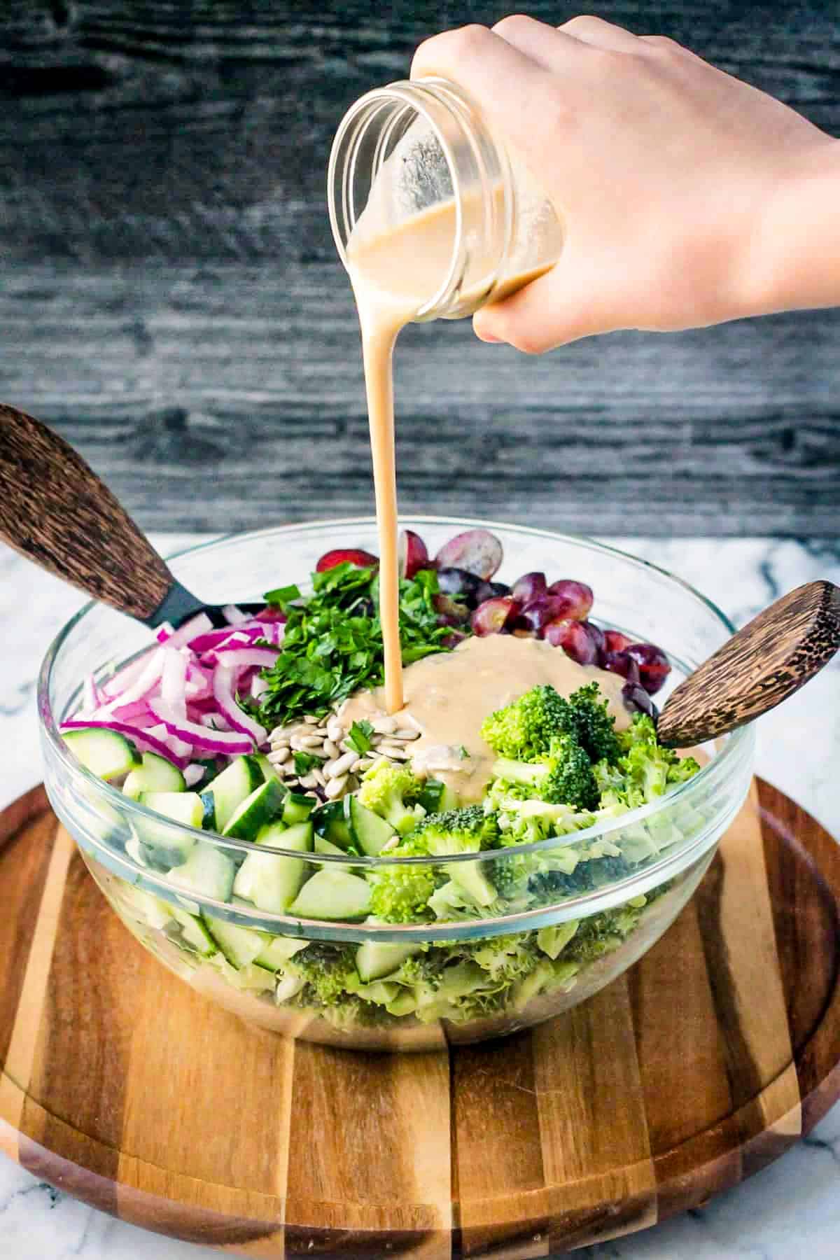 Tahini salad dressing being poured over the broccoli salad.