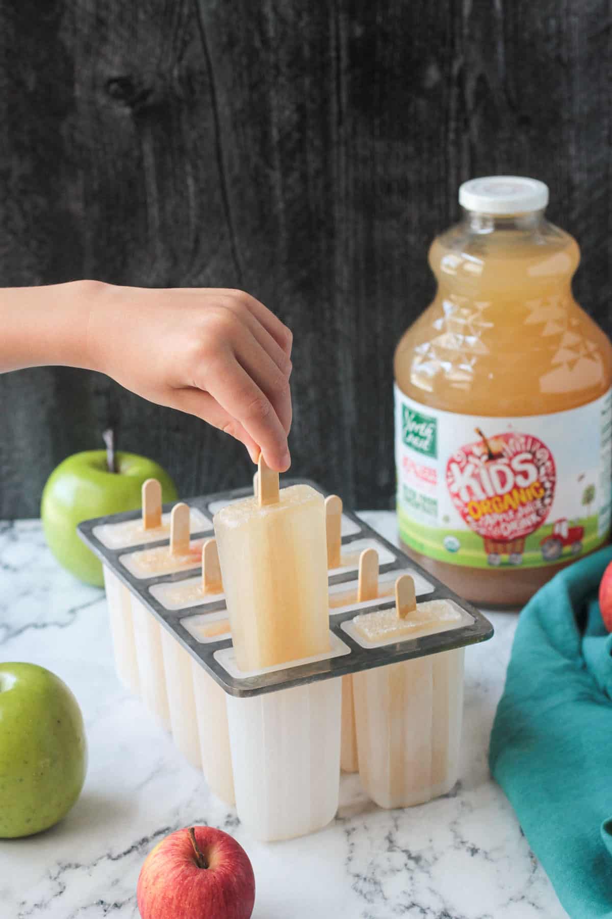 Child's hand pulling out a popsicles from the molds.