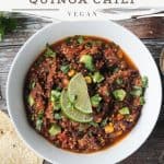 Bowl of quinoa chili with black beans, diced avocado, and lime slices.
