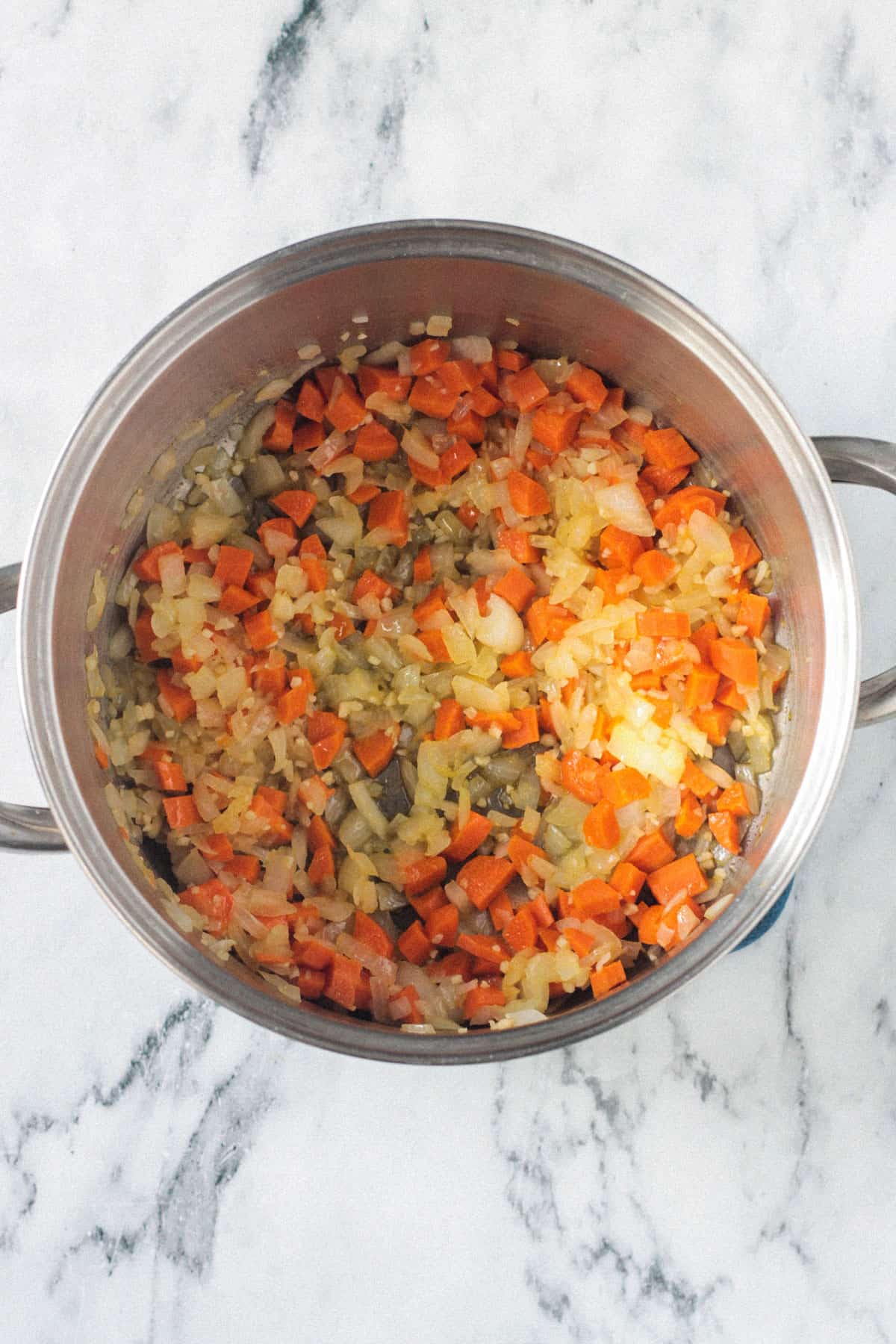 Sautéed vegetables in a soup pot.