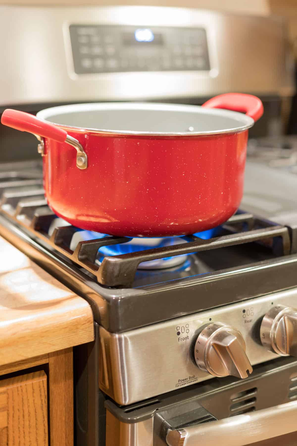 Red enamel pot over a flame on a gas range stove.