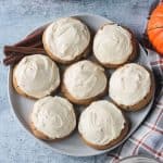 7 pumpkin cookies with white frosting on a plate.