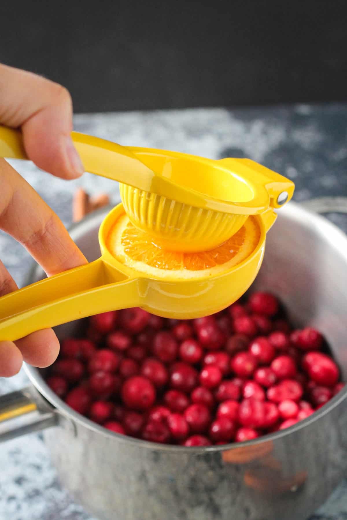 Juicing an orange into the pot of cranberries