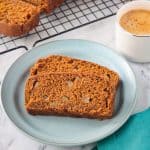 Two slices of vegan pumpkin bread on a blue plate next to a cup of coffee.