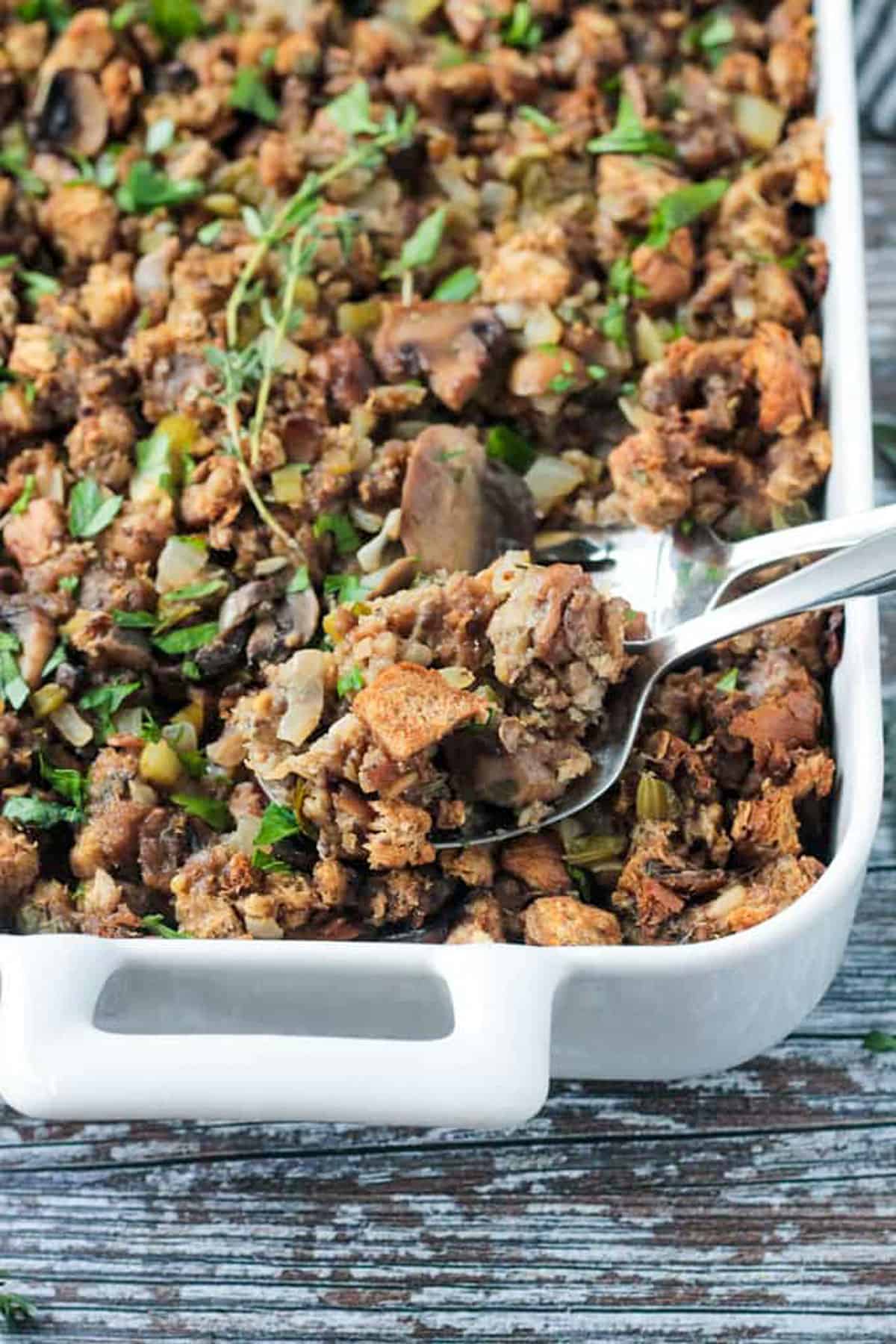 Spoonful of vegan mushroom stuffing being lifted out of the baking dish.