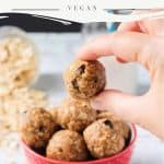 Hand holding one oatmeal peanut butter ball above a red bowl.