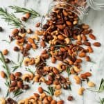 Jar of roasted nuts spilled out onto a marble table top.