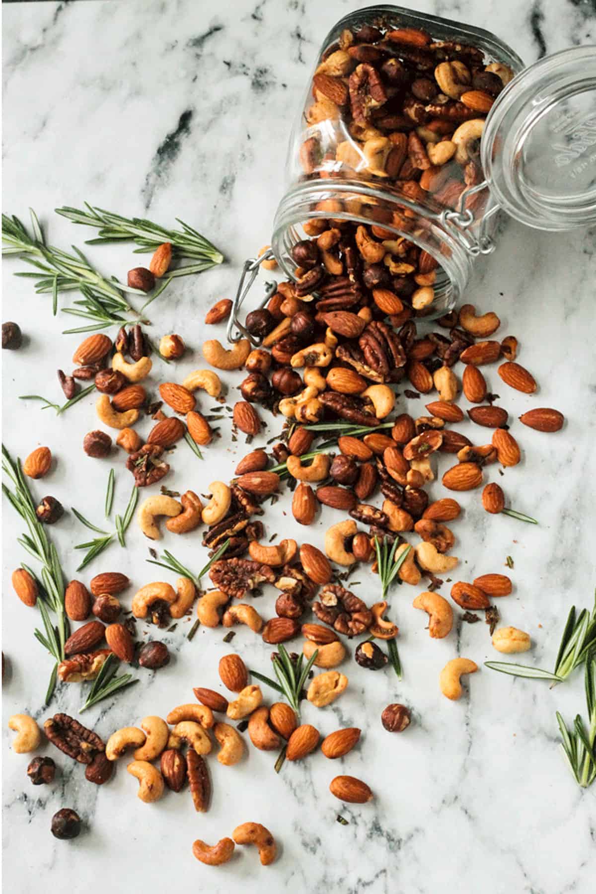 Jar of roasted nuts spilled out onto a marble table top.