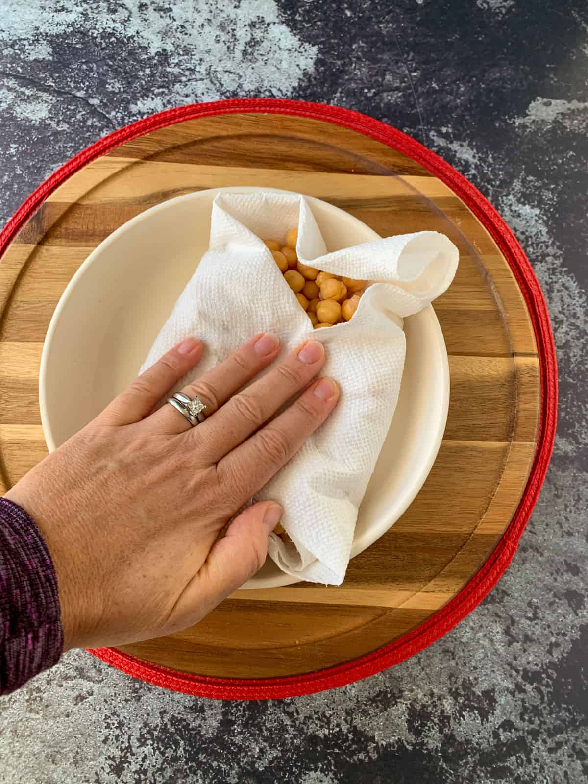 Patting chickpeas dry with a paper towel.