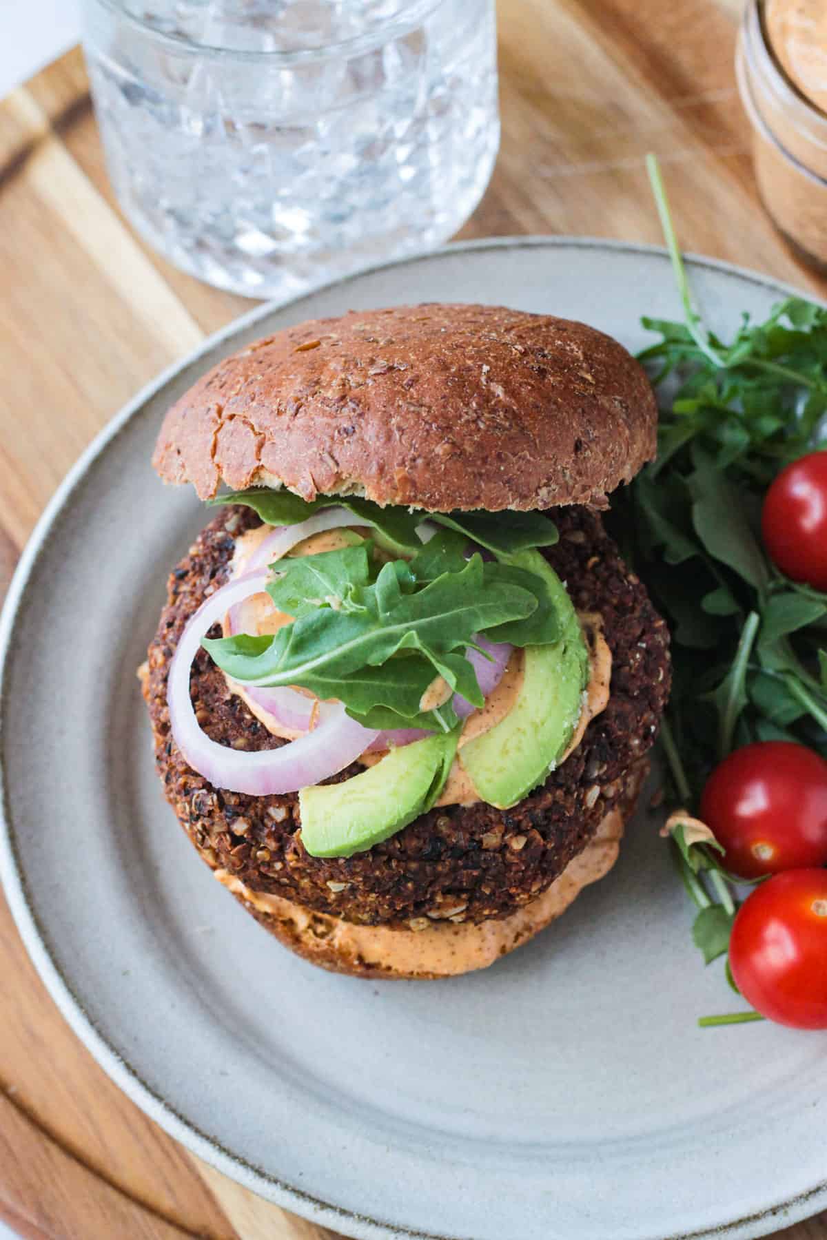 Close up of arugula, red onion, and avocado toppings on a burger.
