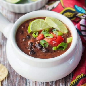 Bowl of Vegan Black Bean Soup with a bowl of lime wedges.
