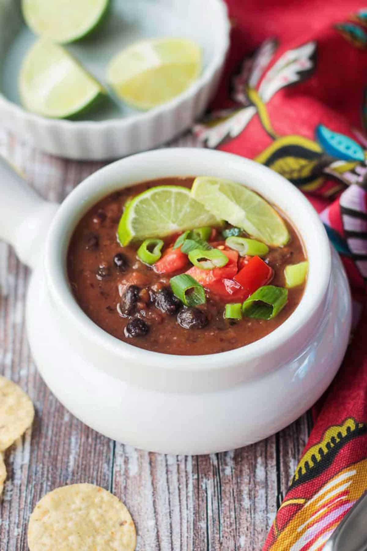 Bowl of Vegan Black Bean Soup with a bowl of lime wedges.