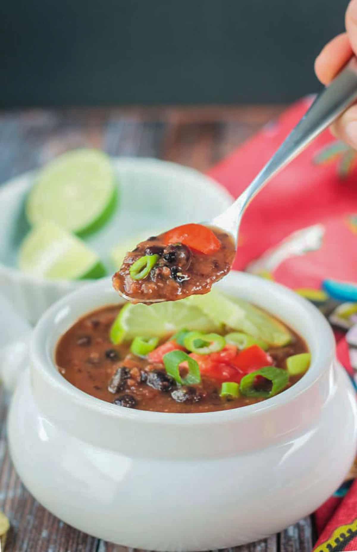 Spoonful of black bean soup being lifted from a bowl.