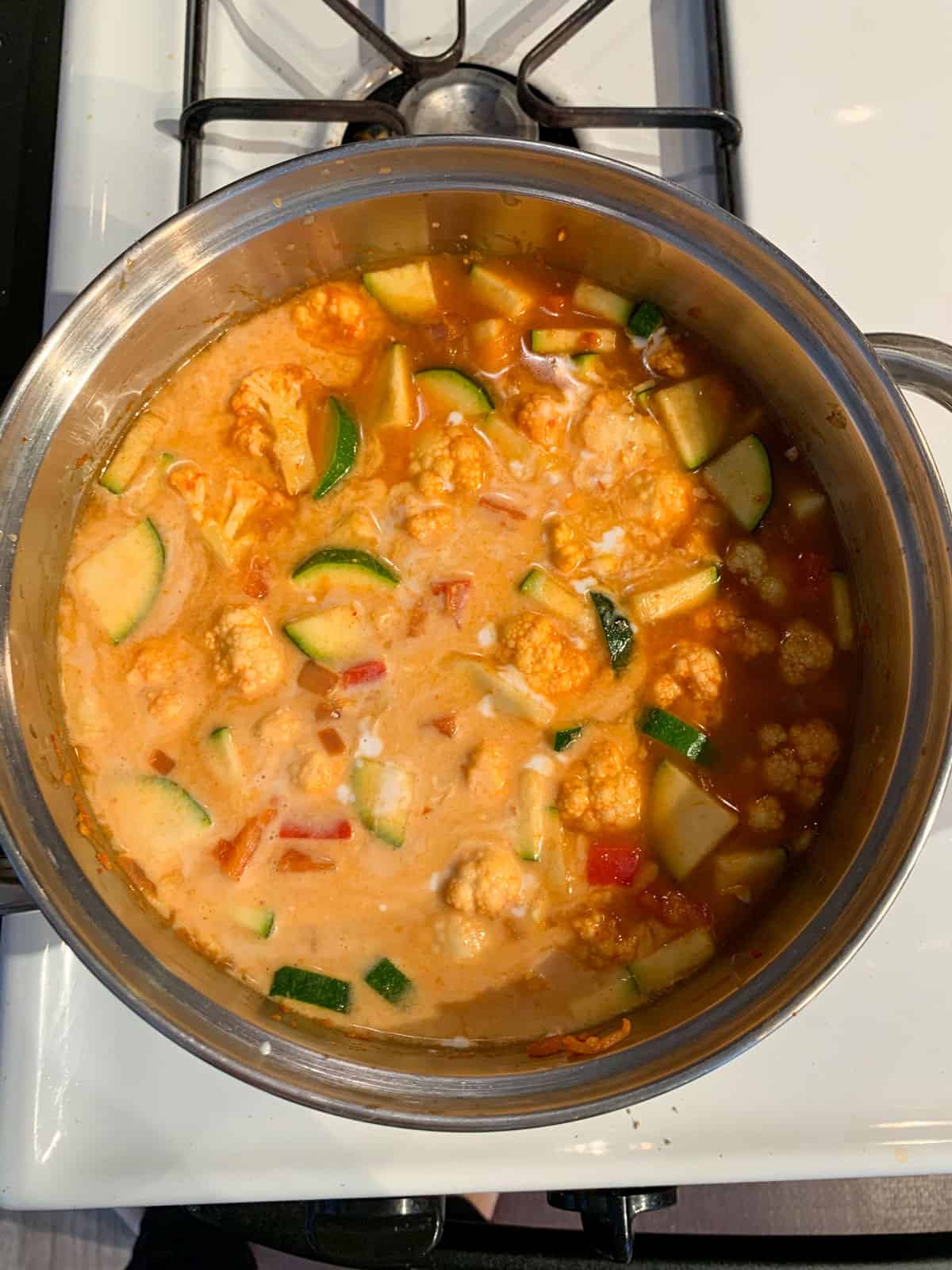 Adding broth and coconut milk to the pot.