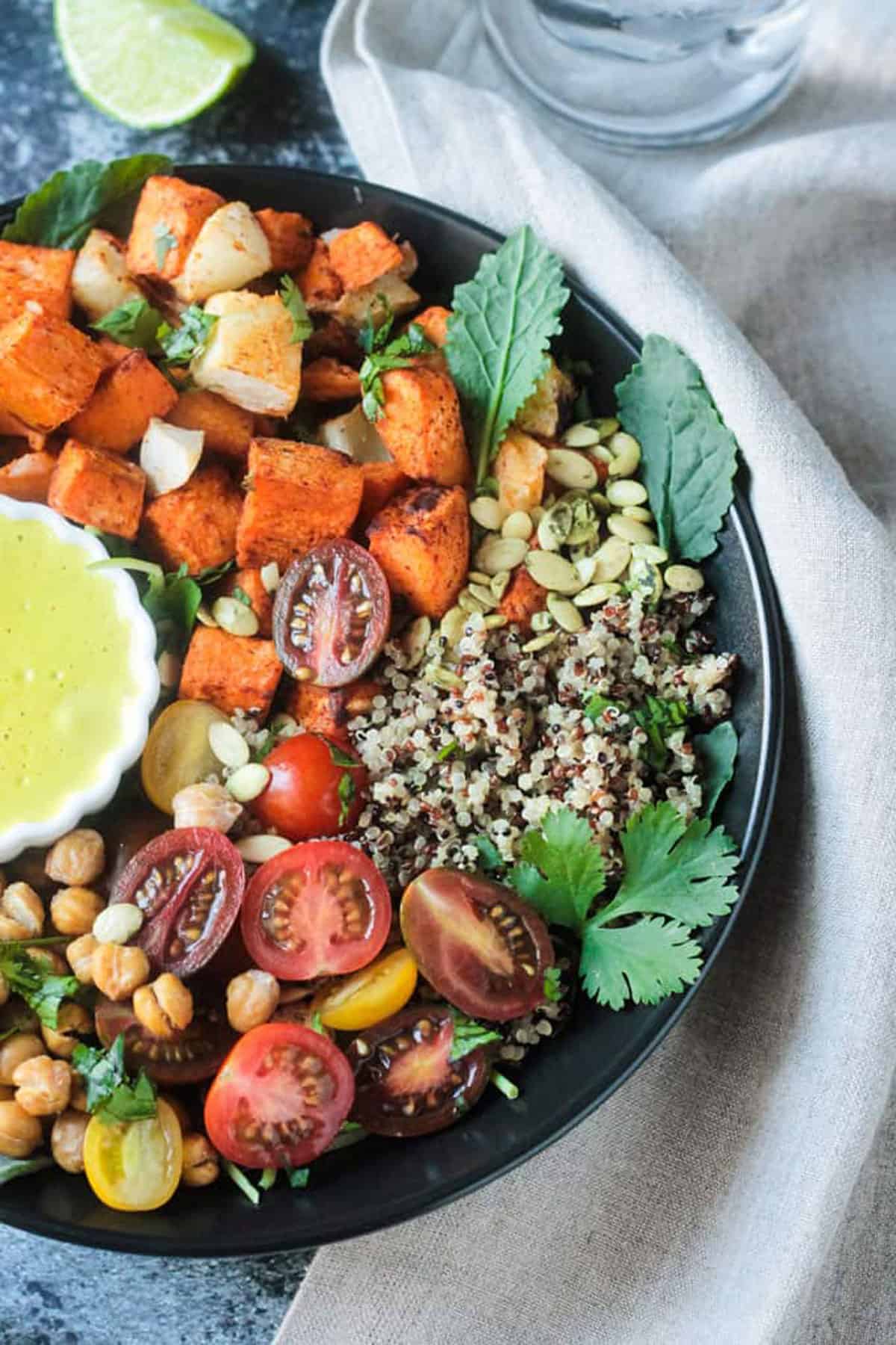 Close up of quinoa, baby kale, and grape tomatoes in a dinner bowl.