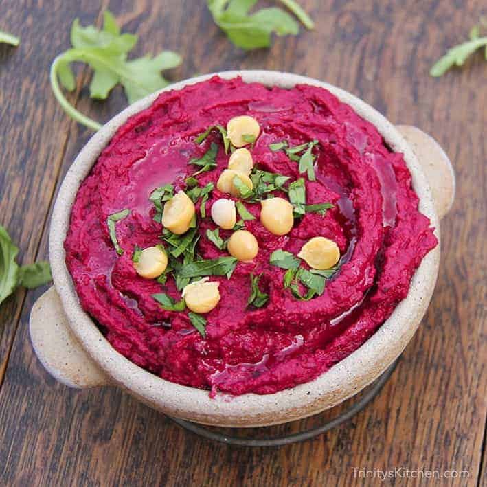 Bowl of beetroot hummus topped with chickpeas.