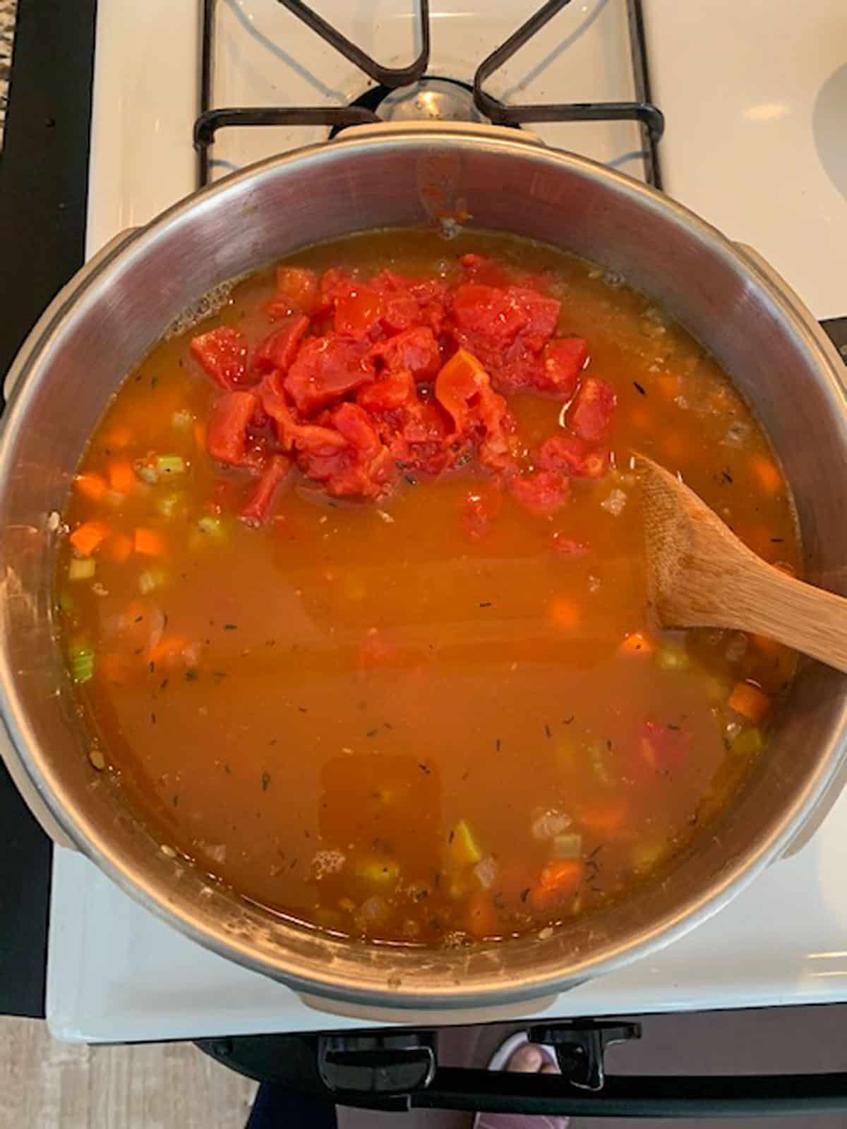 Adding diced tomatoes to the soup.