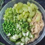 Quinoa, grapes, celery, peas, green onions, and cucumbers in a bowl.