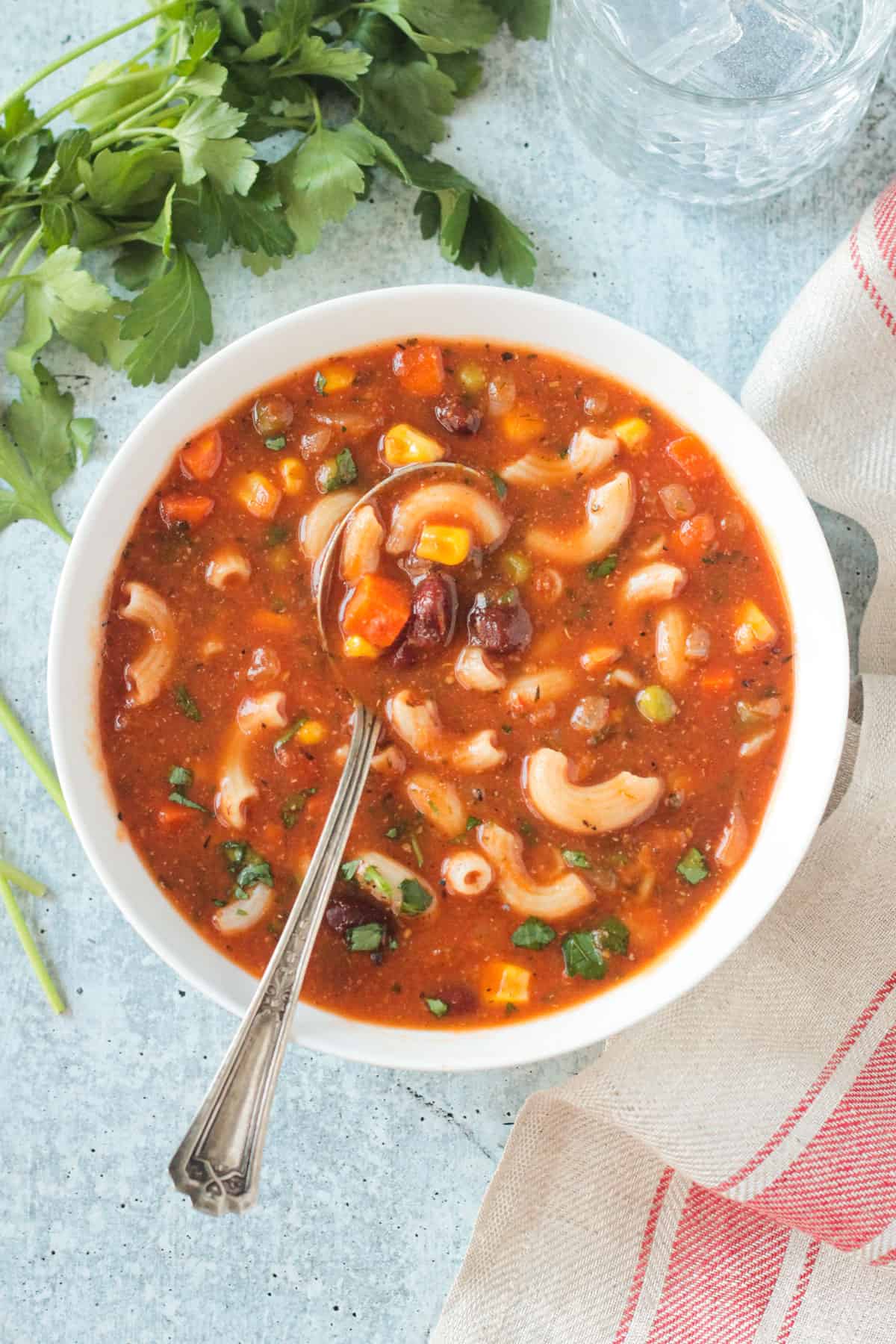 Metal spoon in a bowl of vegan minestrone soup.