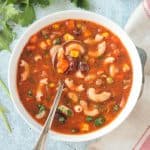 Spoon in a bowl of minestrone soup with noodles.