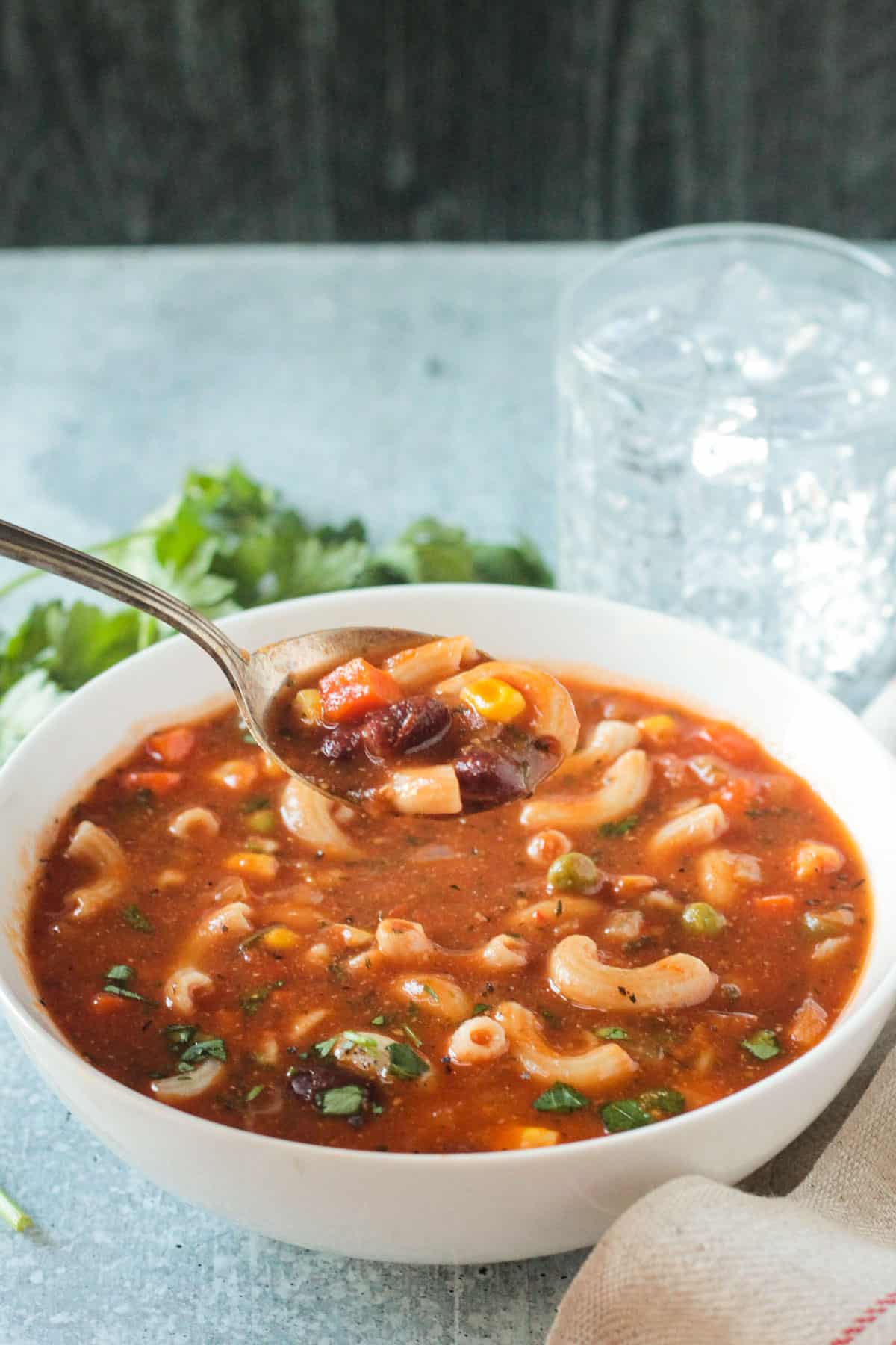 Spoonful of minestrone soup being lifted from a bowl.