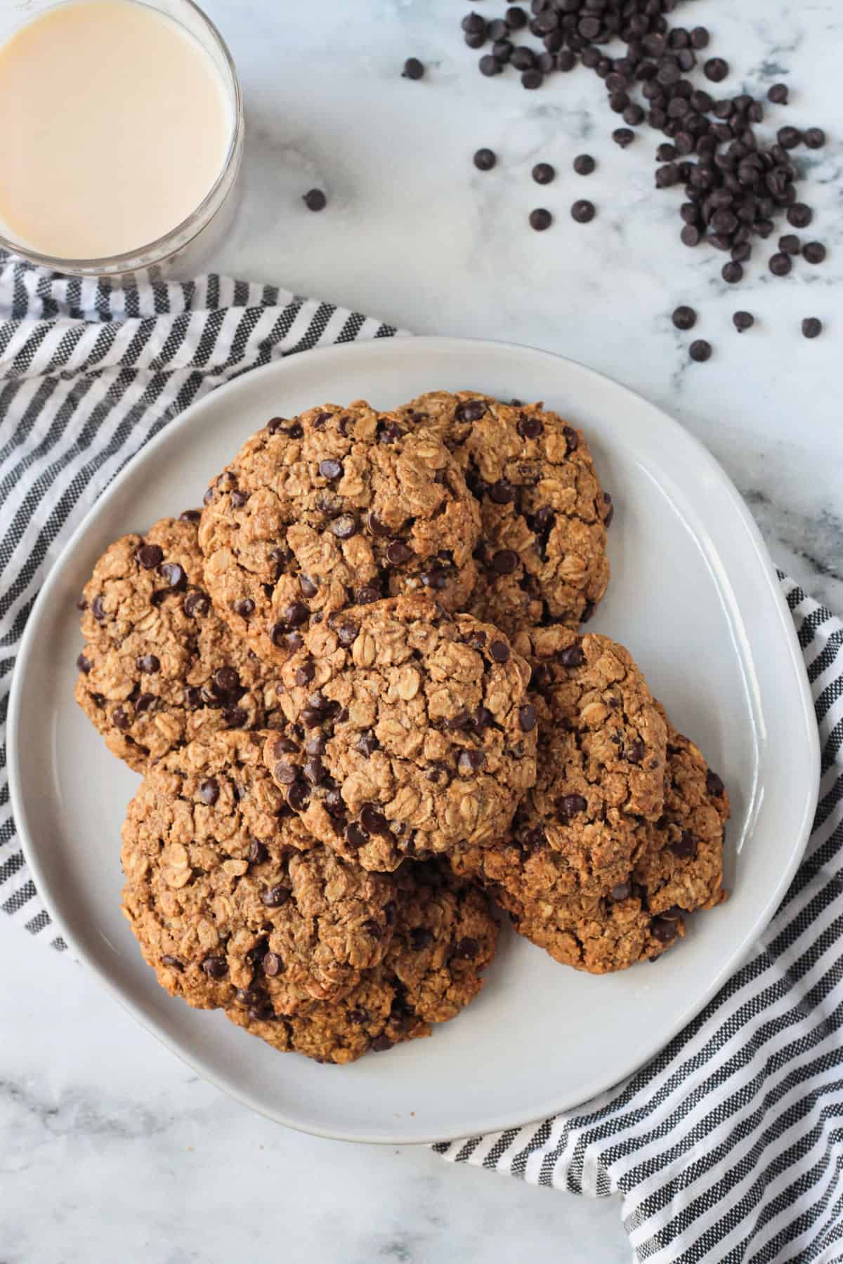 Overhead view of a pile of vegan oatmeal chocolate chip cookies on a plate.