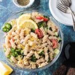 Bowl of vegan pasta salad with rotini noodles, broccoli, cucumber, artichokes, and tomatoes.