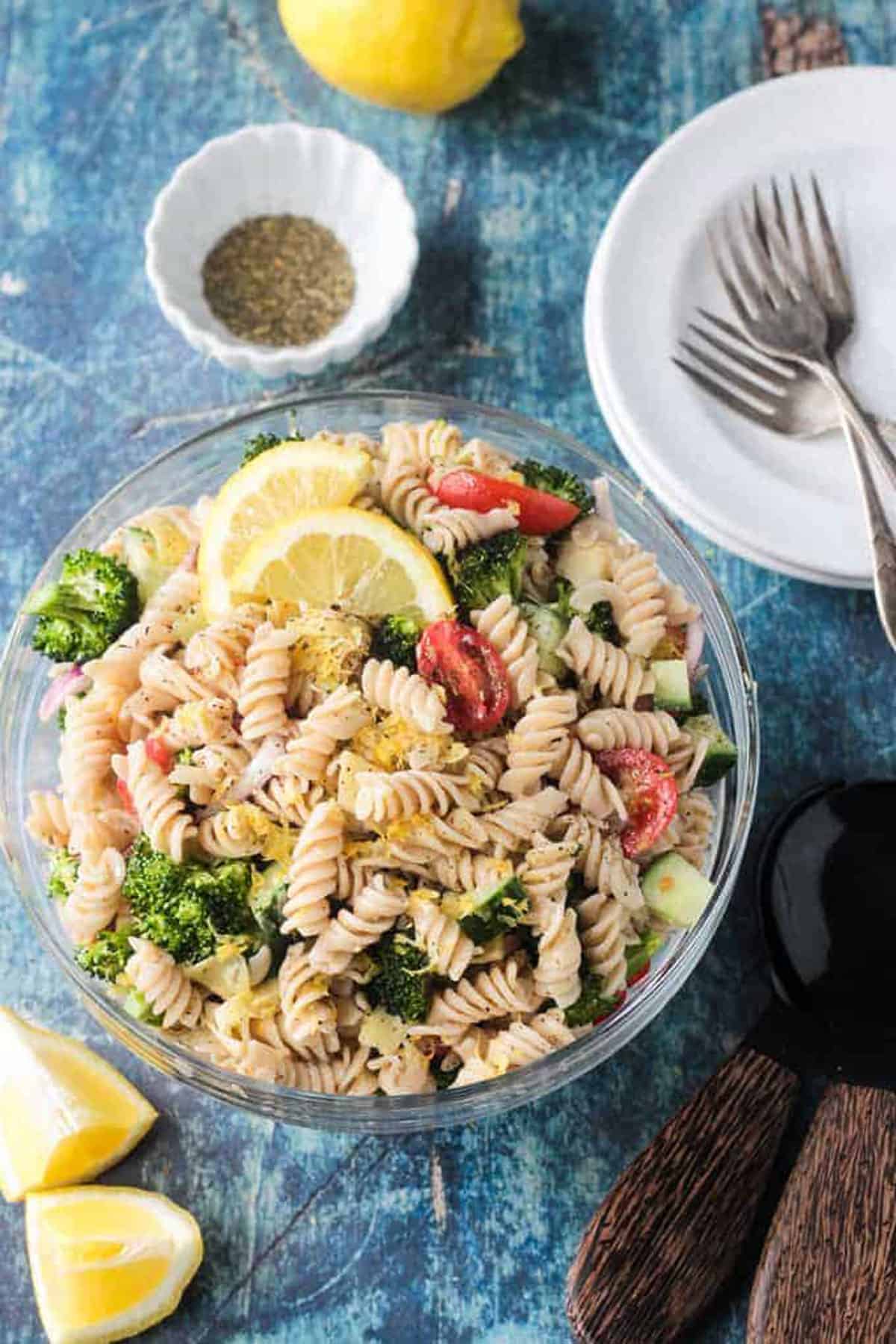 Bowl of vegan pasta salad with rotini noodles, broccoli, cucumber, artichokes, and tomatoes.