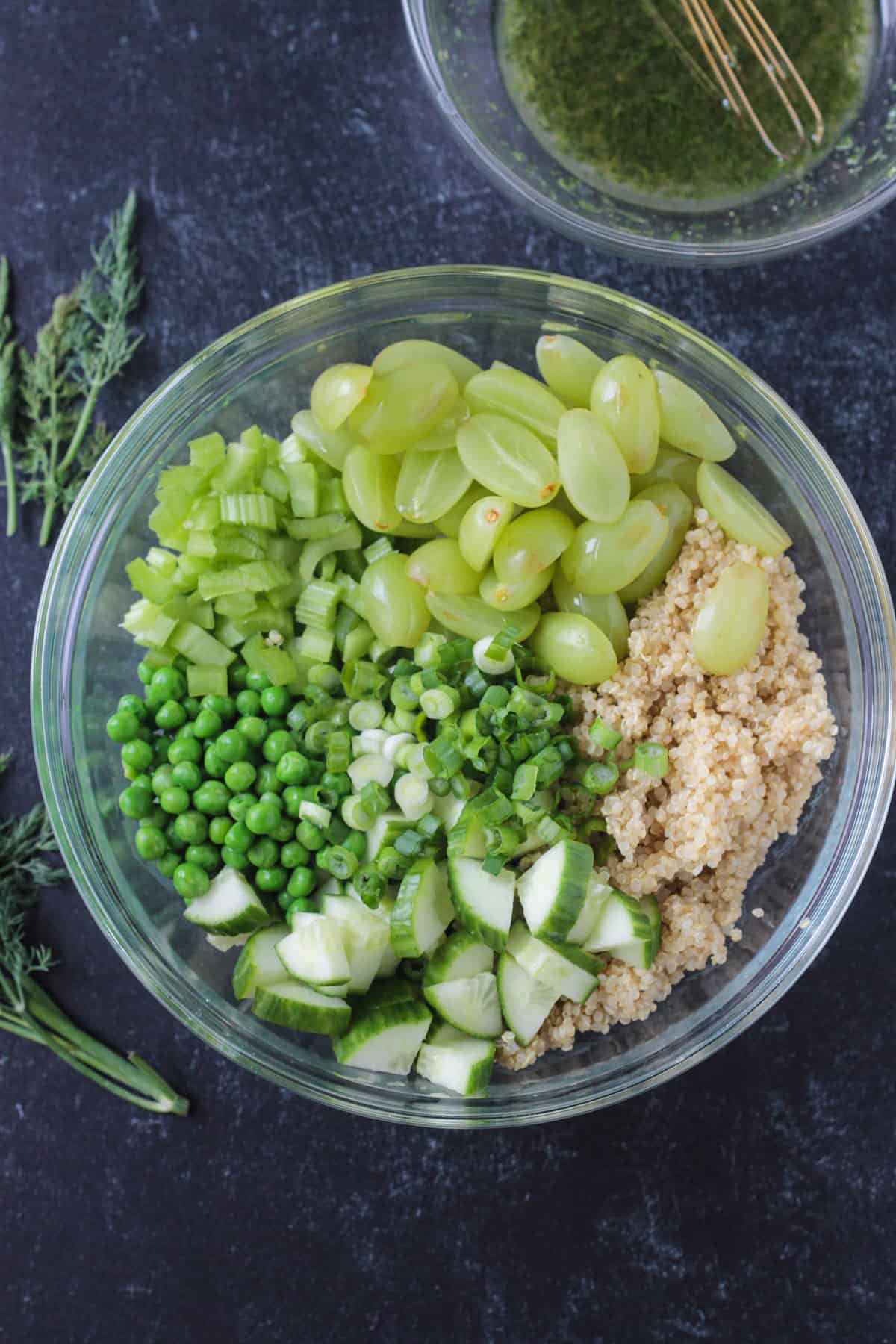 Quinoa, grapes, celery, peas, green onions, and cucumbers in a bowl.