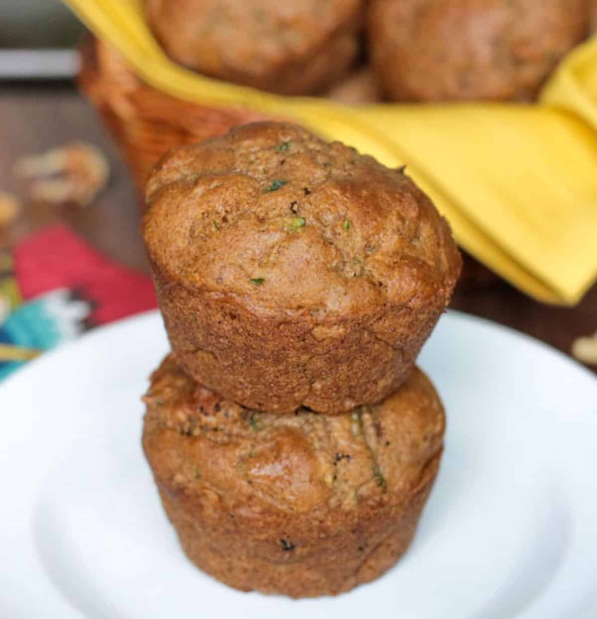 Two vegan zucchini muffins stacked on a white plate.