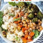 Roasted vegetables and brown rice in a bowl with tahini sauce.