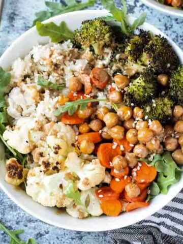 Dinner bowl of rice, cauliflower, broccoli, carrots, and chickpeas topped with a sprinkle of sesame seeds.