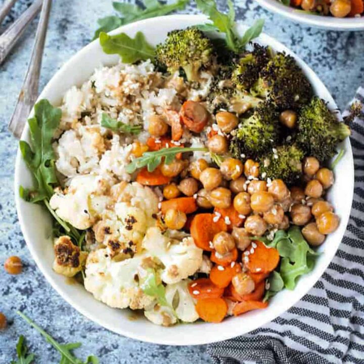 Dinner bowl of rice, cauliflower, broccoli, carrots, and chickpeas topped with a sprinkle of sesame seeds.