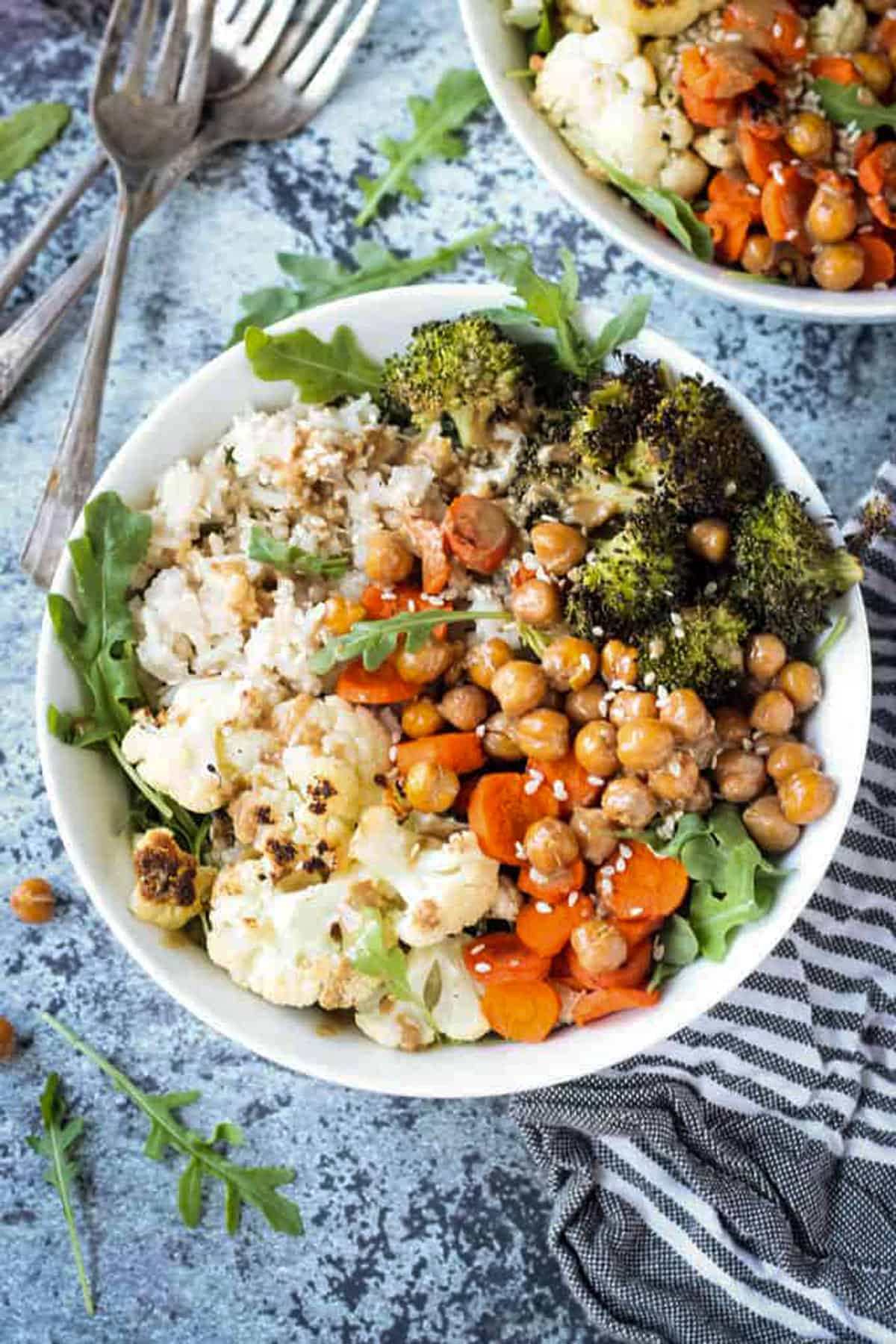 Bowl of rice, cauliflower, broccoli, carrots, and chickpeas topped with a sprinkle of sesame seeds.