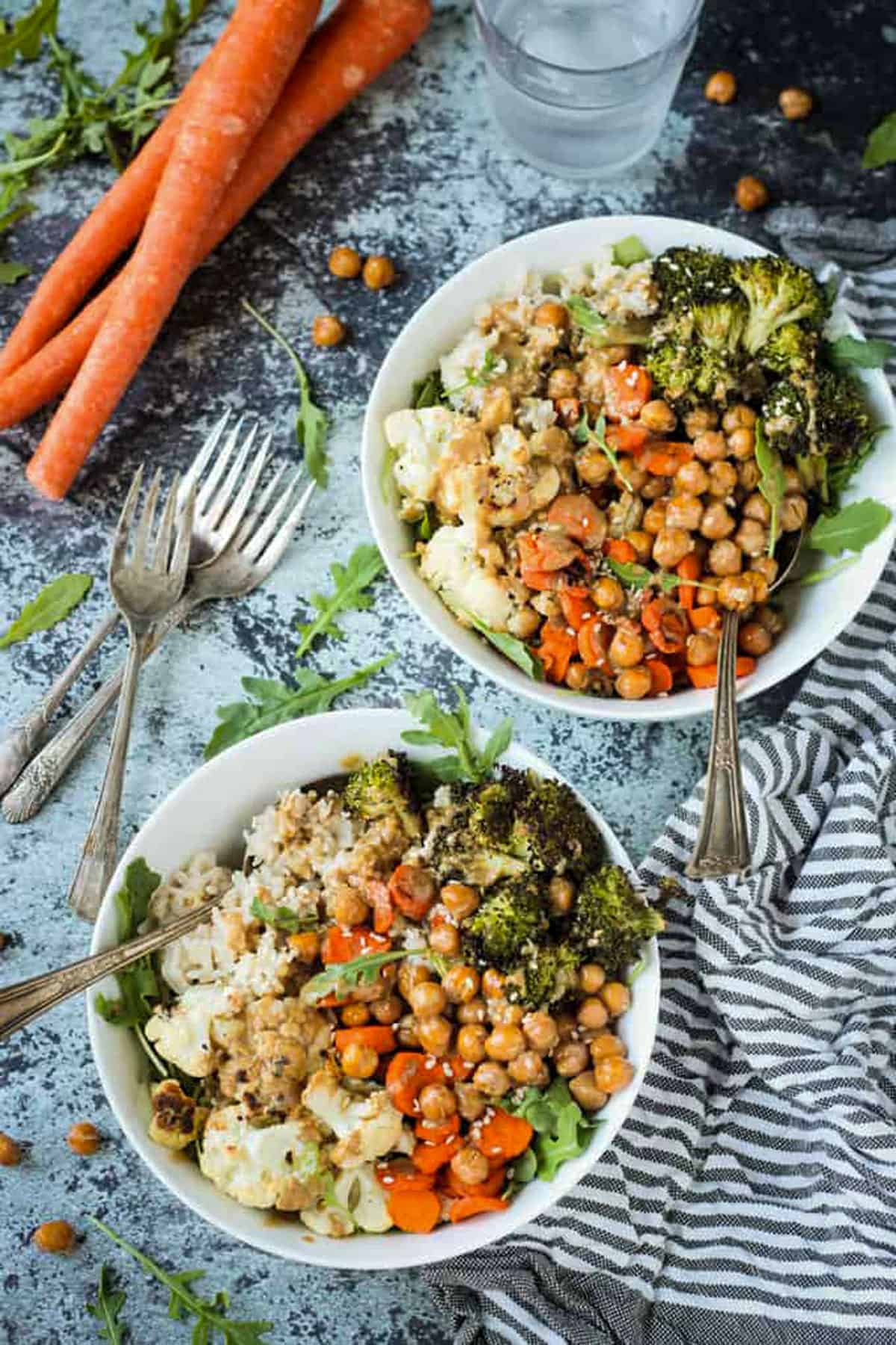 Two veggie rice bowls next to a striped dish cloth.