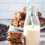 Tall glass of milk next to a stack of two cake squares.