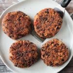 4 cooked burger patties on a plate.