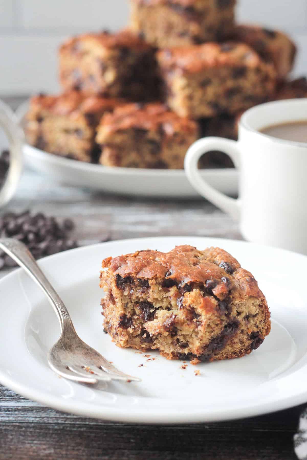 Piece of banana snack cake on a plate with a bite missing.