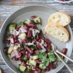 Red kidney bean salad on a gray plate with a baguette slice.