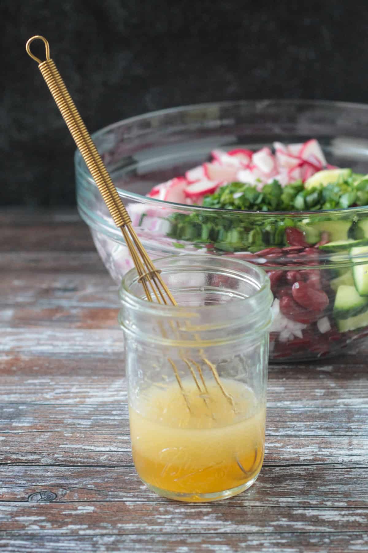 Dressing in a jar with a whisk.