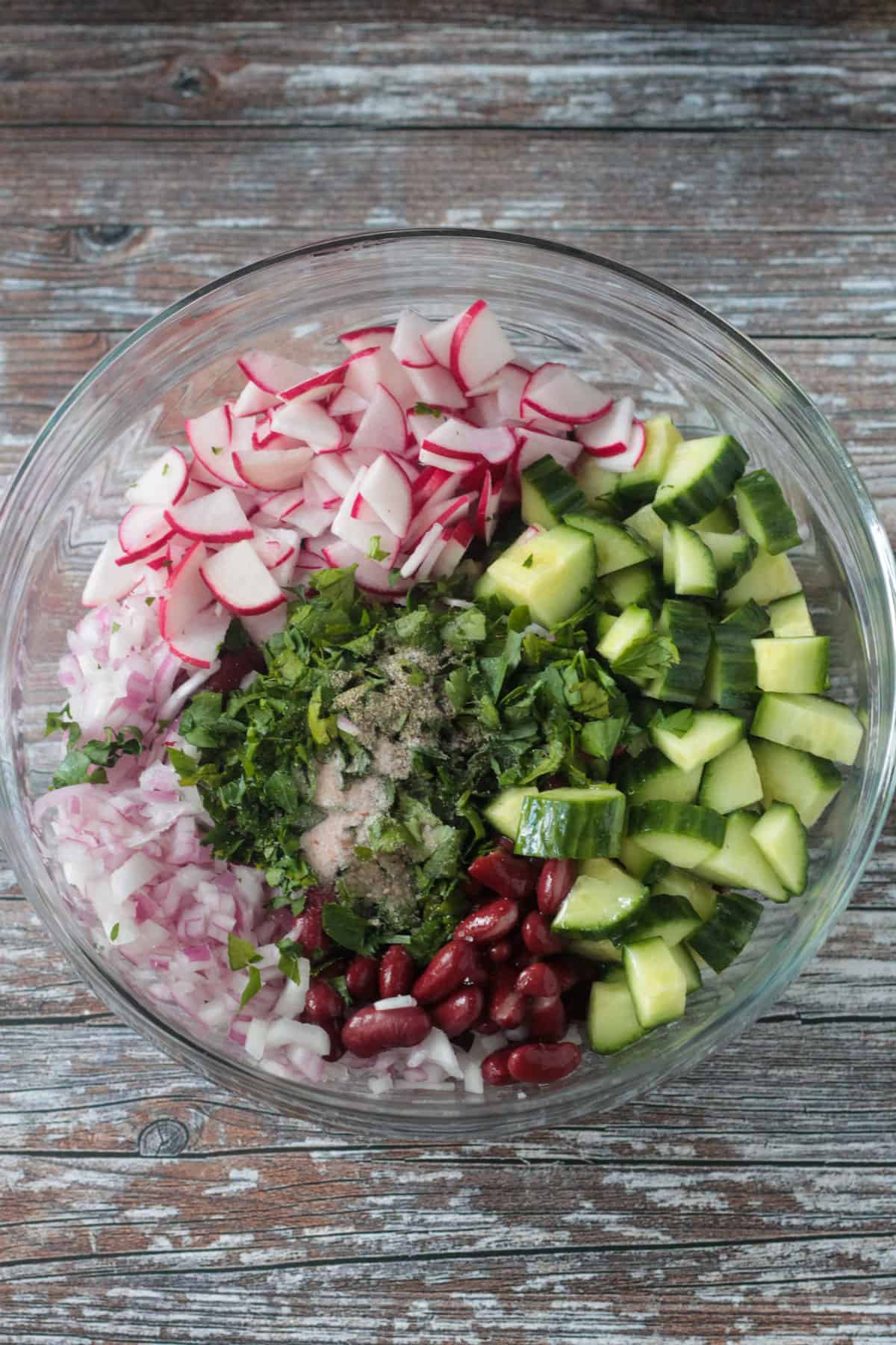 Chopped parsley and dry seasonings added to the bowl of diced vegetables.