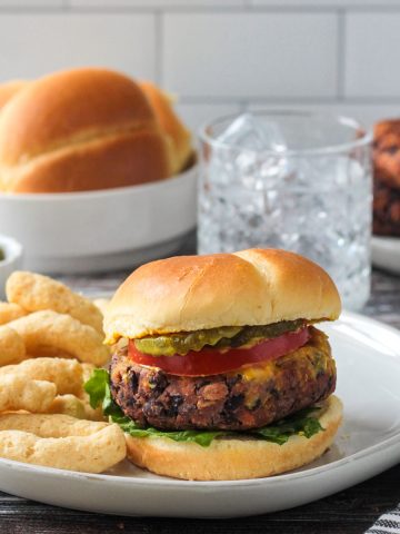 Spicy Bean Burger on a bun with toppings next to chips.