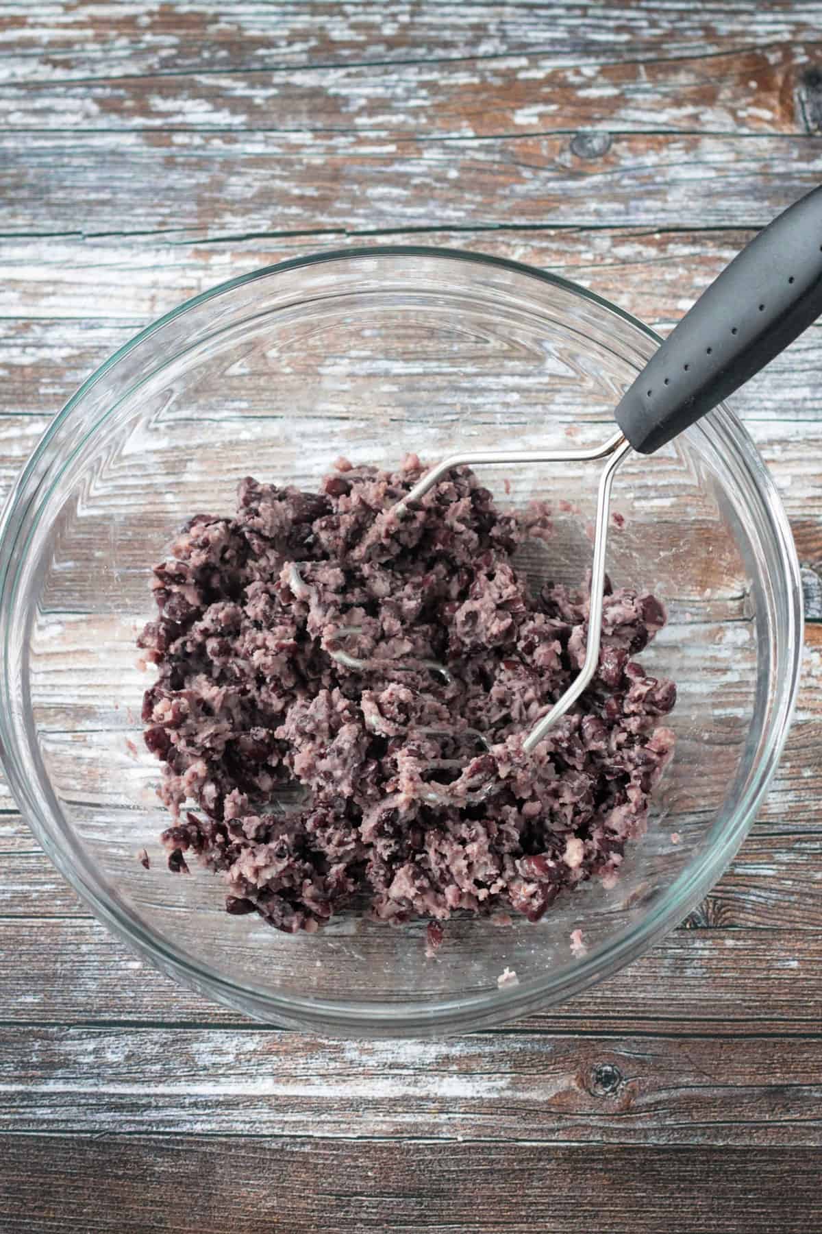 Mashed black beans in a mixing bowl.