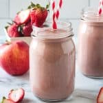 Strawberry Apple Smoothie in a glass with two red and white striped straws.